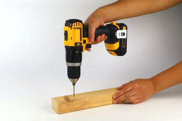 A female carpenter drilling a hole in a piece of timber