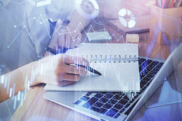 Financial charts displayed on woman's hand taking notes background. Concept of research. Double exposure