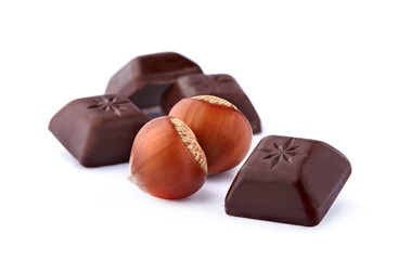 Closeup shot of cut dark chocolate with hazelnuts on white background.