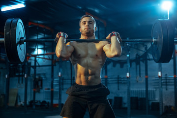 Fototapeta na wymiar Caucasian man practicing in weightlifting in gym. Caucasian male sportive model training with barbell, looks confident and strong. Body building, healthy lifestyle, movement, activity, action concept.