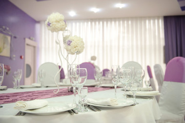 close up photo of a white arranged table with lila details in a wedding banquet hall