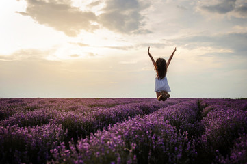 back view of a woman in white dress jumping in the lavander field
