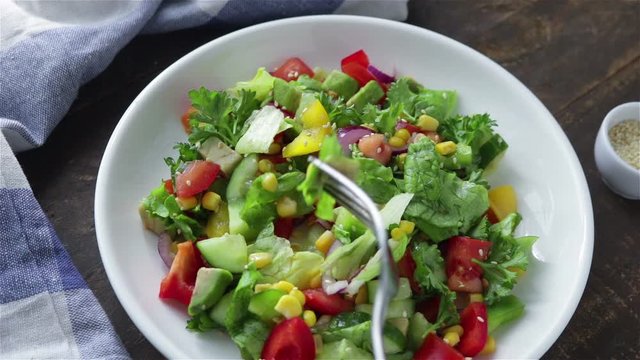 eat fresh vegetarian salad with avocado tomatoes cucumber parsley corn lettuce  frist person view shot