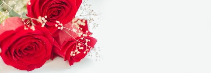 Close up red roses with dewdrops on the petals and dried flowers lie on a white background. Valentine's Day background, Birthday, Wedding. Banner. Holiday and gift concept. Copy space