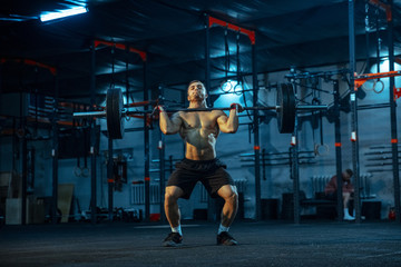 Obraz na płótnie Canvas Caucasian man practicing in weightlifting in gym. Caucasian male sportive model training with barbell, looks confident and strong. Body building, healthy lifestyle, movement, activity, action concept.