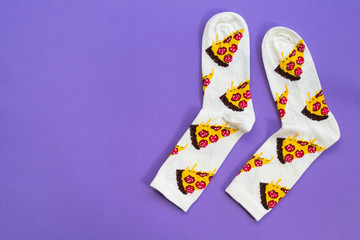 two multi-colored socks on a purple background, concept