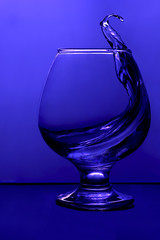 Cognac pouring into a glass in blue
