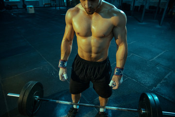 Caucasian man practicing in weightlifting in gym. Caucasian male sportive model preparing for training, looks confident and strong. Body building, healthy lifestyle, movement, activity, action concept