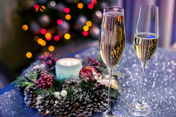 Glasses with champagne against the background of a Christmas tree in the lights. Home magical...