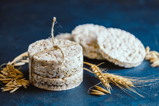 Stack of rice cakes. American puffed rice cakes. Healthy snacks with ears of wheat on classic blue concrete surface