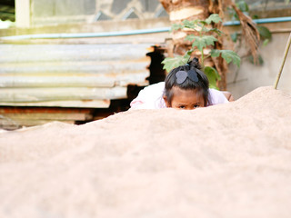 An Asian girl is playing happily in the sand on a holiday.
