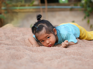 An Asian girl is playing happily in the sand on a holiday.