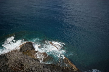 Waves crushing onto rocks viewed from a cliff
