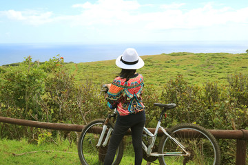 Female biker admiring the scenic Pacific ocean from Rano Kau volcano on Easter Island, Chile