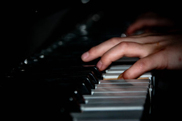 Piano player over black background closeup shot. Children's hands on the piano keys