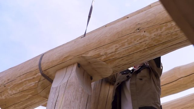 Construction industry concept, bottom view of a carpenter trying to unhook the cable construction. Clip. The process of installing wooden roof of a new building.