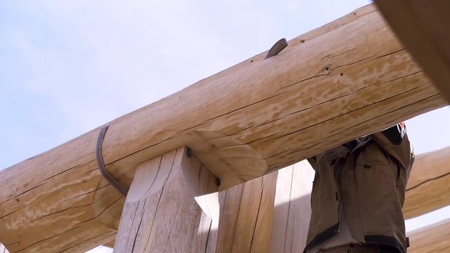 Construction industry concept, bottom view of a carpenter trying to unhook the cable construction. Clip. The process of installing wooden roof of a new building.