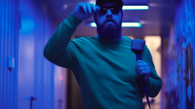 Handsome bearded man walking in the neon light tunnel. Slowmotion. Hand held shot.