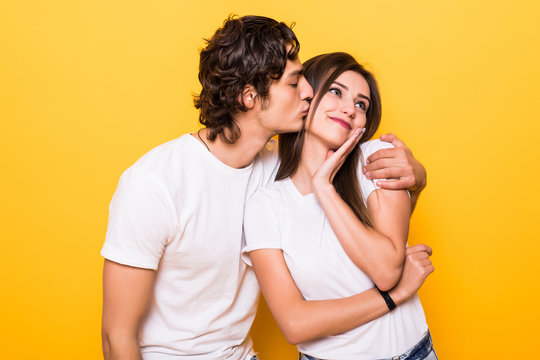 Young lovely couple posing together making selfie and kissing over yellow background