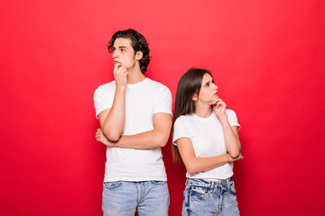 Young couple of friends thinking touching their chins looking up isolated on red background