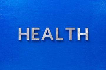 the word health laid with silver metal characters on blue painted wooden board in central flat lay...