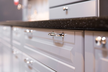 Light wooden furniture in the kitchen, cabinets and drawers with beautiful handles.