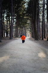 a happy boy is running with a winter suit in the forest.