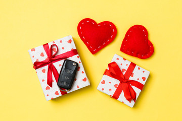 Top view of car key on gift box and red textile hearts on colorful background. Present for Valentine's Day concept