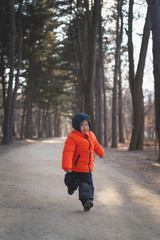 a happy boy is running with a winter suit in the forest.