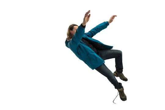 A second before falling. Caucasian young man falling down in moment with bright emotions and facial expression. Male model in casual clothes on white. Shocked, scared, screaming. Copyspace for ad.
