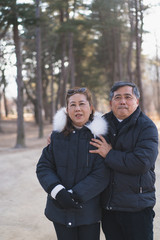 a happy elder couple is smiling and take a picture together in the forest in the winter season.