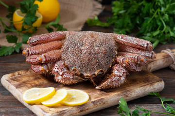 Raw crab on a wooden Board on a brown wooden table. Rustic style	