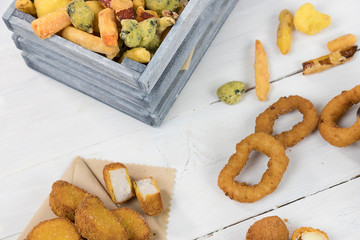 Fast food, group photo of fried food: onion rings, french fries, chicken nuggets, olive ascane on white wooden table