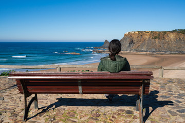 Woman looking at Praia de Odeceixe beach in Costa Vicentina, Portugal