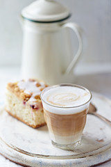 Coffee with milk and a piece of yeast cake on bright background. 