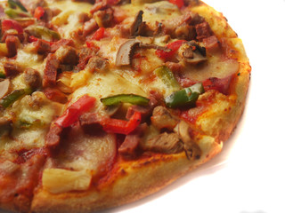Pizza in round shape, topped with meat, ham, mushroom and veggies