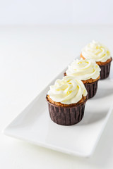 Carrot cupcakes with cream on a white plate.
