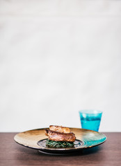 Eat and drink. Vertical shot of steak with fried foie gras piece on stylish gold plate lying on the table over white background. Luxurious, delicious restaurant food concept. Copy space in upper part