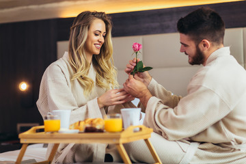 Young happy couple having breakfast in luxury hotel room