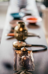 Stylish items. Traditional Turkish metal utensils with coinage on the table. Authentic handmade copper pots and metal cups. Vertical shot. Selective focus. Copy space in upper part