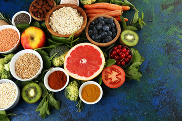 Healthy food clean eating selection: fruit, vegetable, seeds, superfood, cereals, leaf vegetable on rustic background