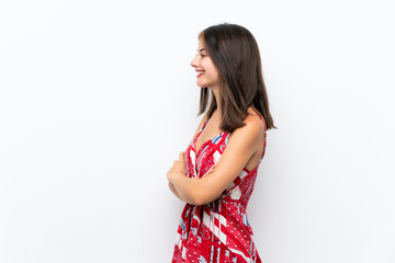 Caucasian girl in red dress over isolated white wall in lateral position