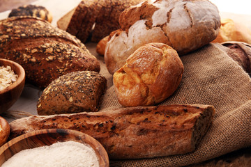 Assortment of baked bread and bread rolls and cutted bread on table background