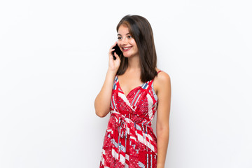 Caucasian girl in red dress over isolated white wall keeping a conversation with the mobile phone