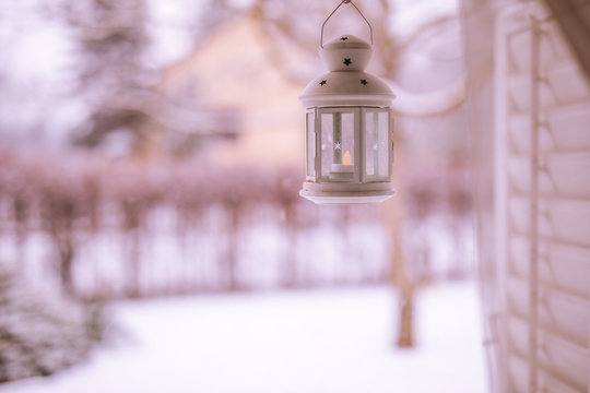 Cozy white lantern on a window with blurred winter landscape seen through the window.