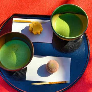 Green matcha tea drink and tea accessories on red background.. Japanese tea ceremony concept.