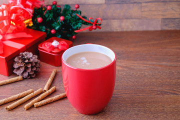 Cup of red chocolate cocoa and red gift box with Christmas tree on white background