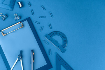 Classic blue colored top view photo of scattered stationery