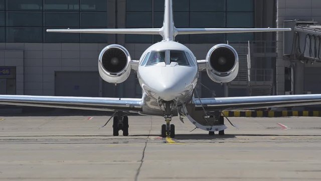 Private jet stands at the airport during summer - mirage effect. Front view of private jet standing at the airport during summer - mirage effect. Shallow depth of field.