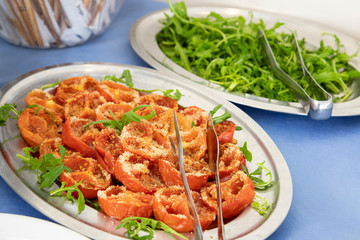 Buffet breakfast in hotel restaurant Tray of baked tomatoes au gratin with arugula